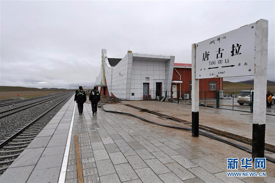 7月26日,中铁十二局集团的工人从青藏铁路唐古拉站站牌前经过.