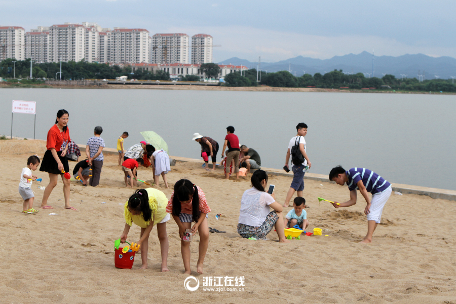 市民趁着周末休息日纷纷带上孩子到湖海塘人工沙滩上觅凉爽