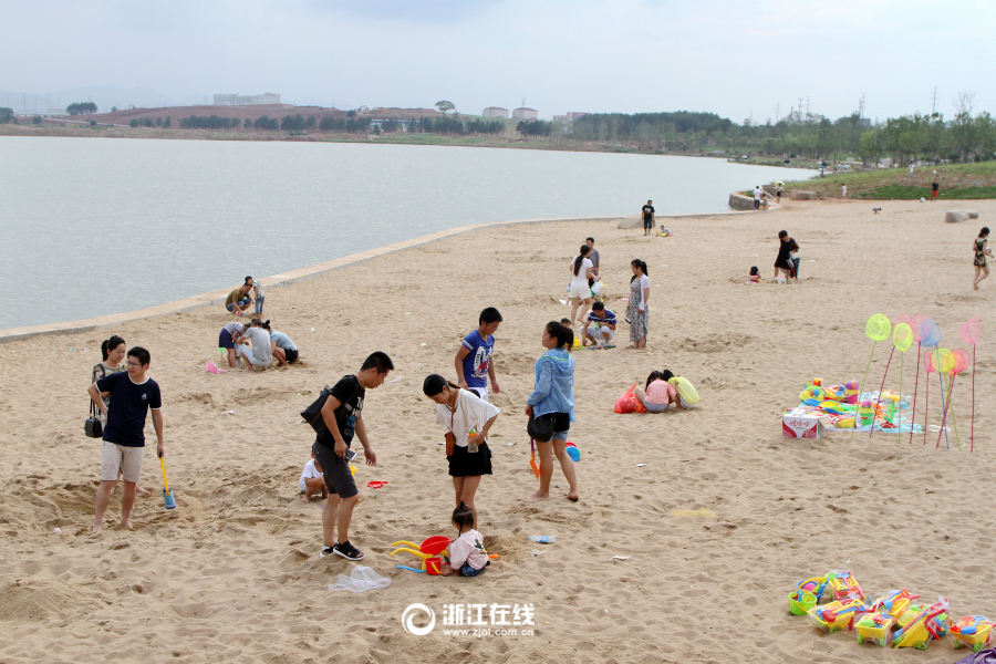 市民趁着周末休息日纷纷带上孩子到湖海塘人工沙滩上觅凉爽