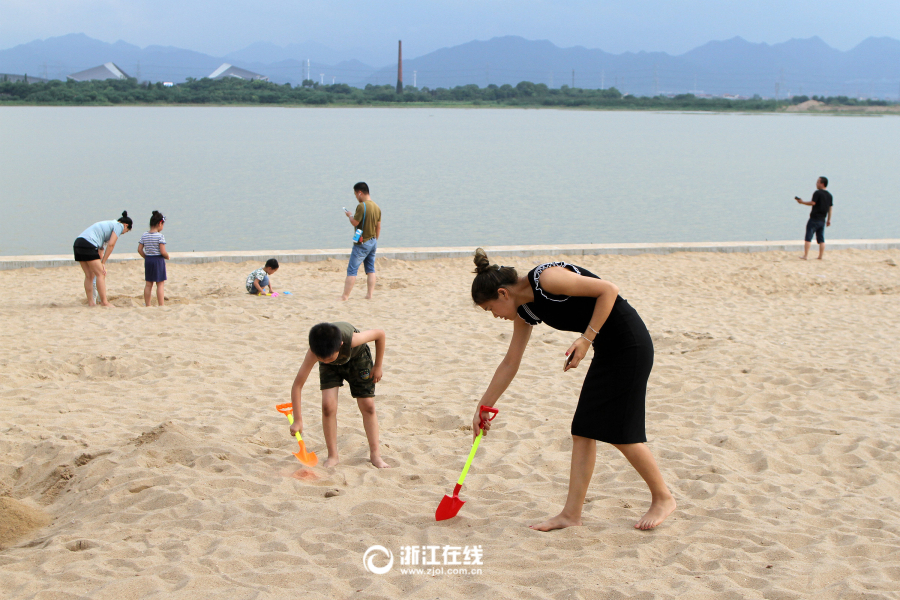 市民趁着周末休息日纷纷带上孩子到湖海塘人工沙滩上觅凉爽