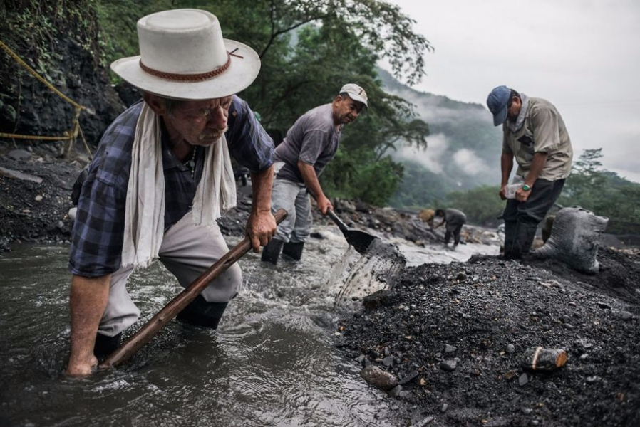 图中,一群挖矿人利用铁锹或双手在河水中寻找宝石,最前面的carlos已是